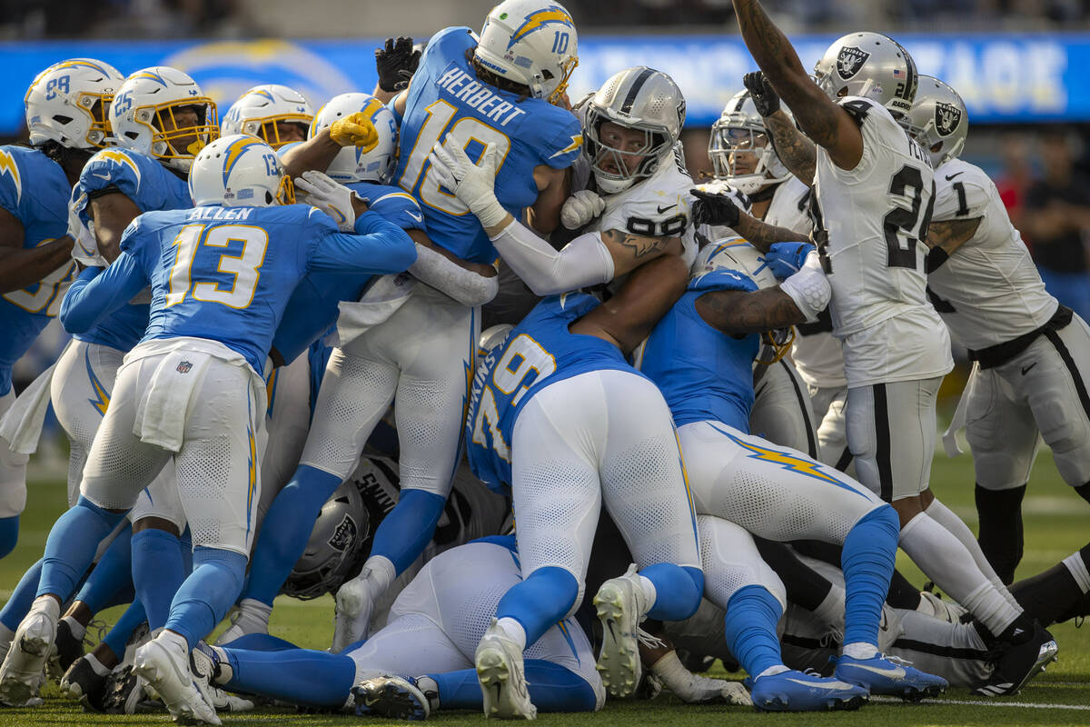 Raiders defensive end Maxx Crosby (98) stops Los Angeles Chargers quarterback Justin Herbert (1 ...