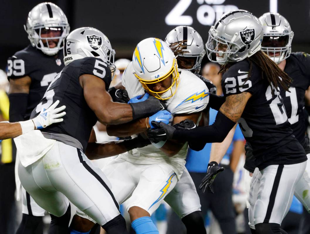 Los Angeles Chargers running back Austin Ekeler (30) is sandwiched between Raiders defense duri ...