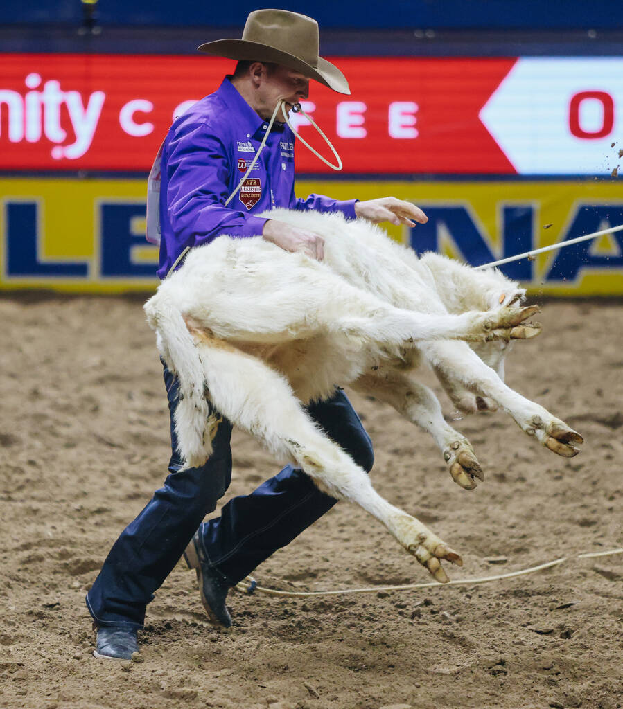 Brushton Minton picks up the calf during tie down roping at the National Finals Rodeo at the Th ...