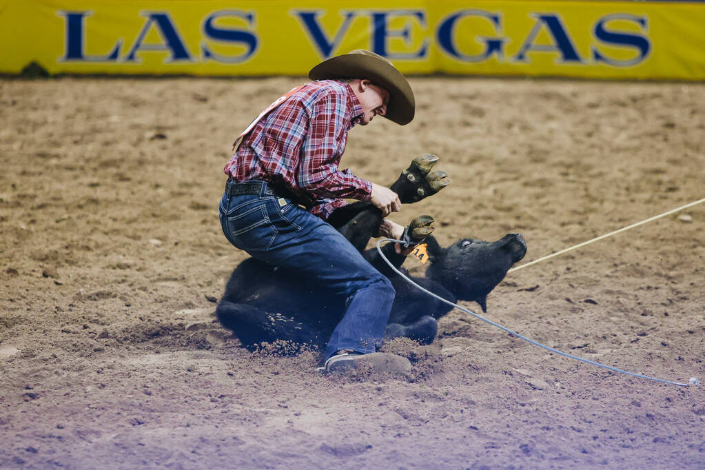 Beau Cooper ties the calf up during tie down roping at the National Finals Rodeo at the Thomas ...