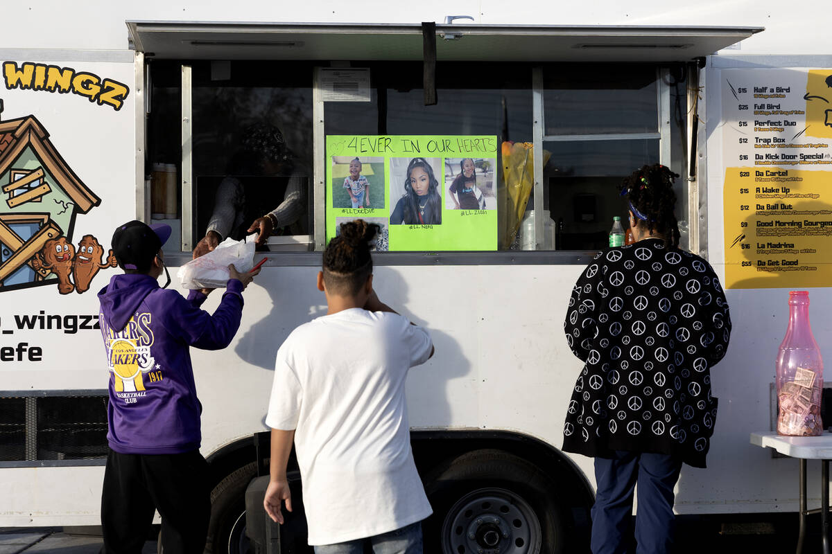 Patrons get food from Trap Wingz food truck during a fundraiser for the family of the mother an ...