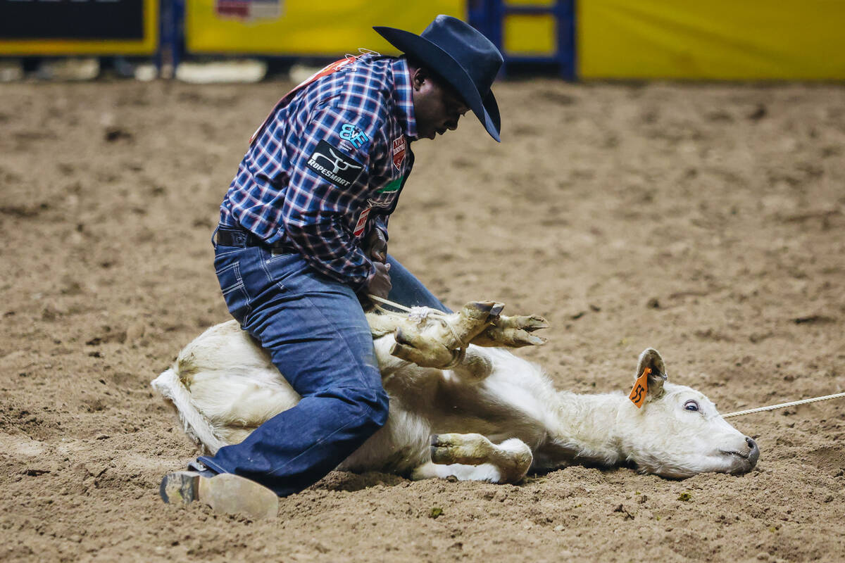 John Douch picks up the calf during tie down roping at the National Finals Rodeo at the Thomas ...