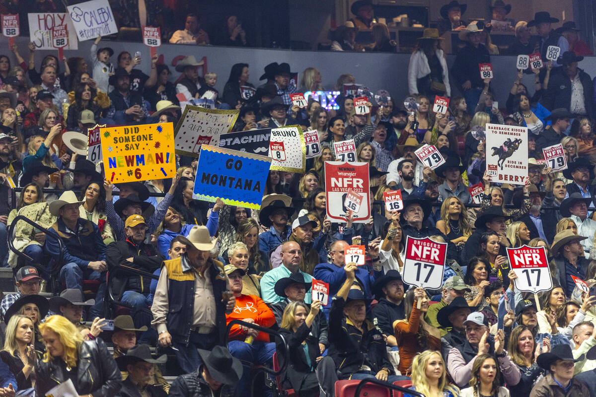 Fans hold signs for their favorite competitors during the final day action of the NFR at the Th ...