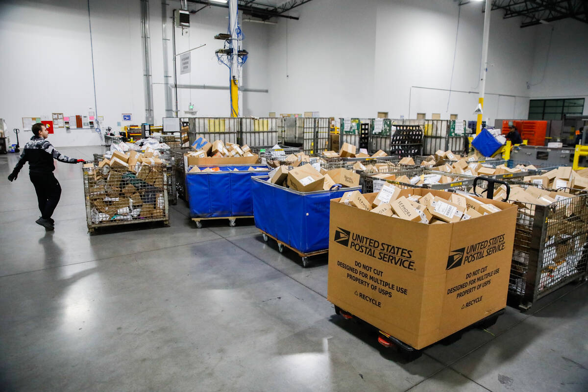 USPS employees sort packages at a distribution center less than two weeks before Christmas on W ...