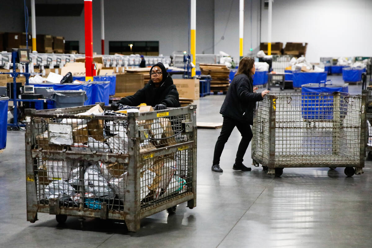 USPS employees sort packages at a distribution center less than two weeks before Christmas on W ...