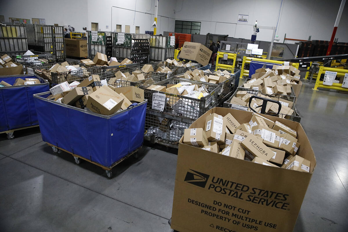 USPS employees sort packages at a distribution center less than two weeks before Christmas on W ...