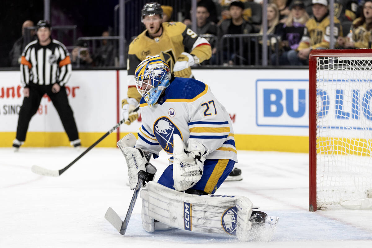 Sabres goaltender Devon Levi (27) saves the puck while Golden Knights center Jack Eichel (9) re ...