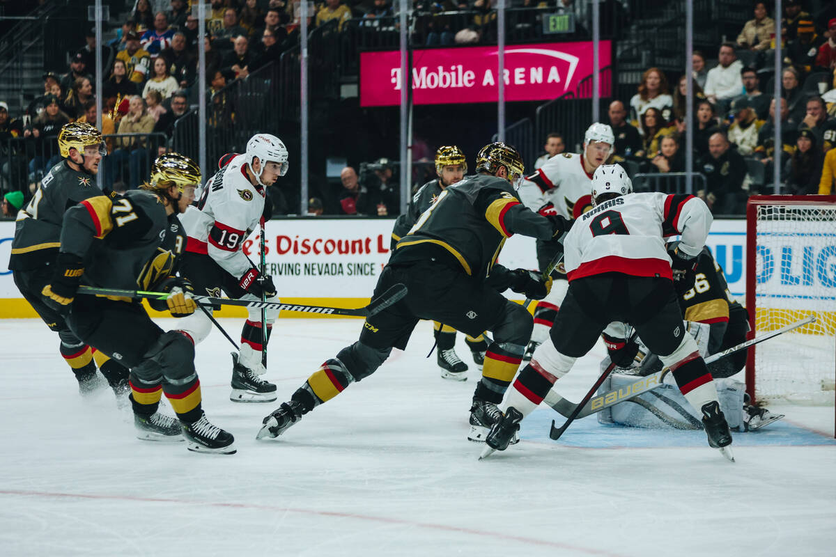 Golden Knights goaltender Logan Thompson (36) saves the puck as Ottawa Senators players and fel ...