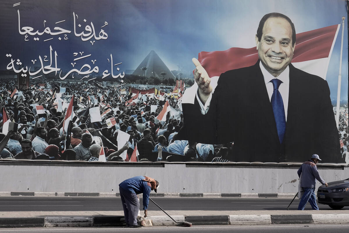 Workers clean the street under a billboard supporting Egyptian President Abdel Fattah el-Sissi ...