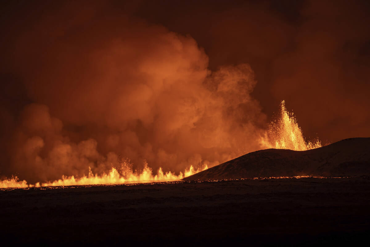 Lava fountains are seen as volcanic eruption started, turning the sky orange, in Grindavik on I ...