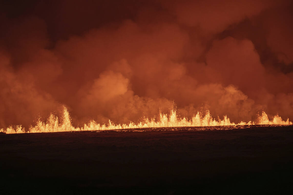 Lava fountains are seen as volcanic eruption started, turning the sky orange, in Grindavik on I ...