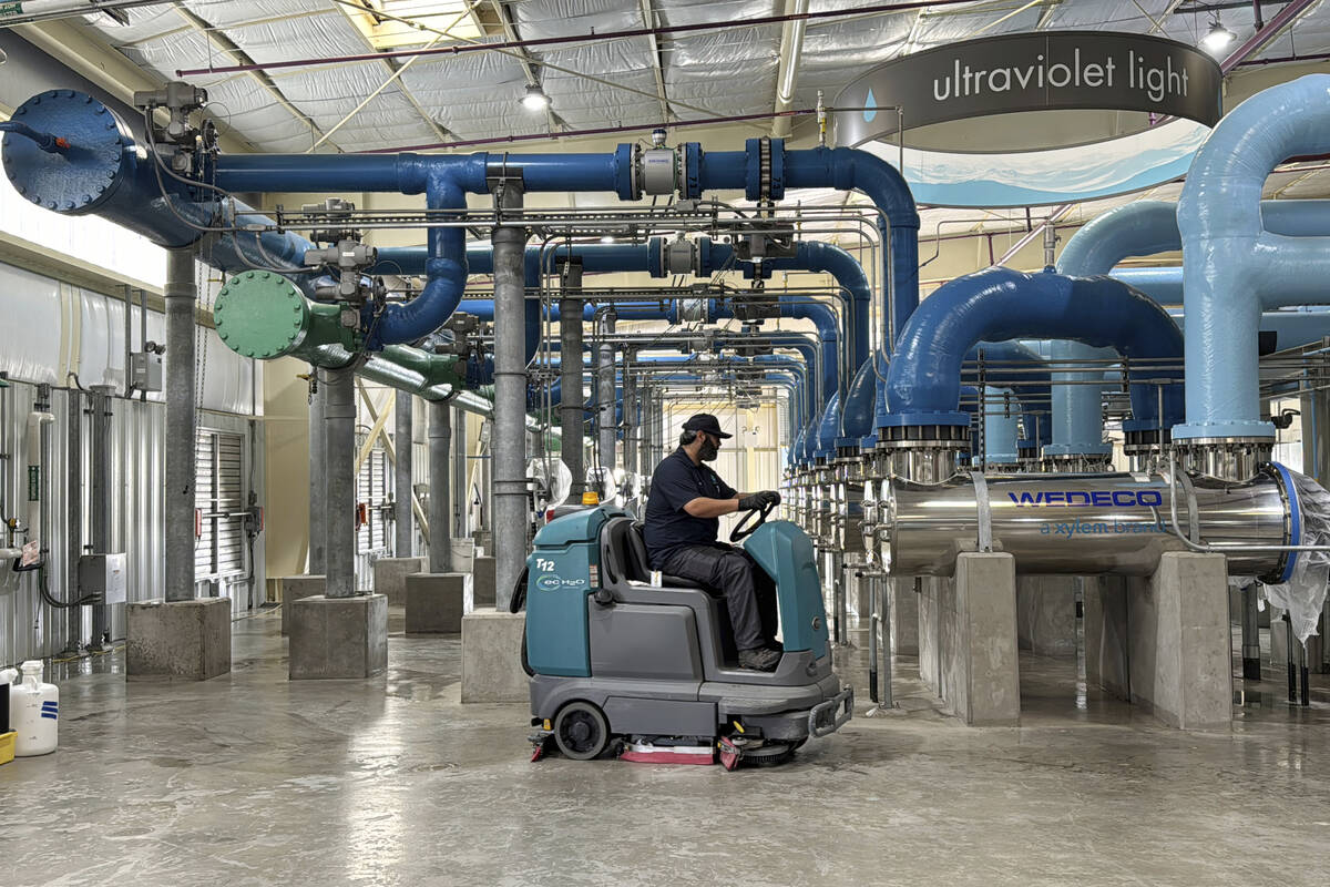 A worker cleans an ultraviolet light disinfection system as part of a water purification proces ...