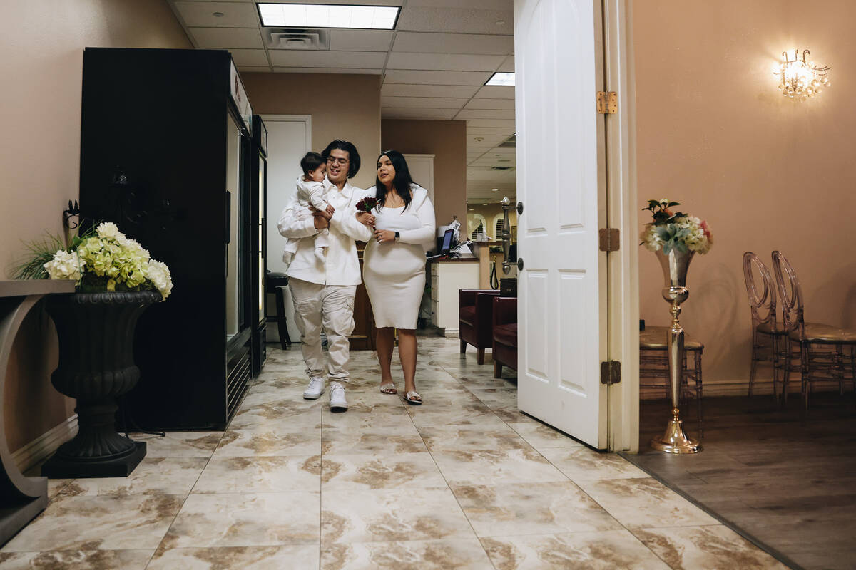 Rudolfo Corlew, left, and Natalie Mazariegos walk down the aisle with their son, Michelangelo, ...