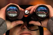 A fan uses binoculars to view the Formula One Las Vegas Grand Prix auto race on Sunday, Nov. 19 ...