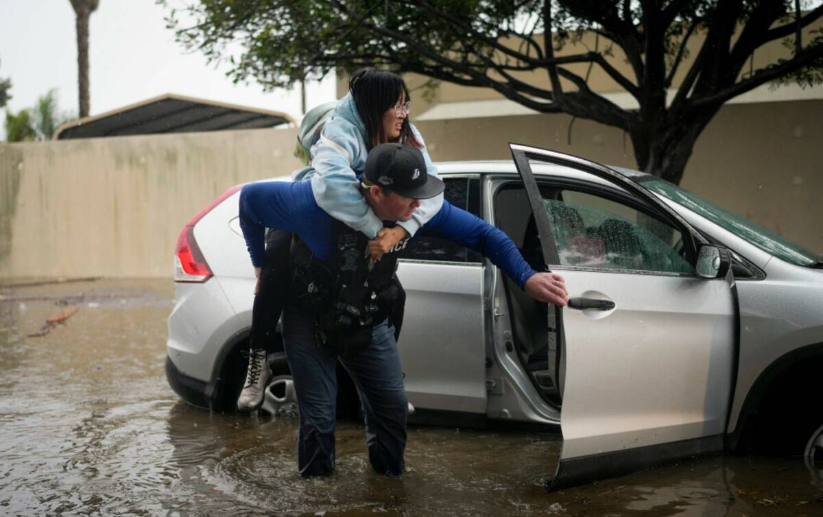 Santa Barbara Police Dept. detective Bryce Ford helps a motorist out of her car on a flooded st ...