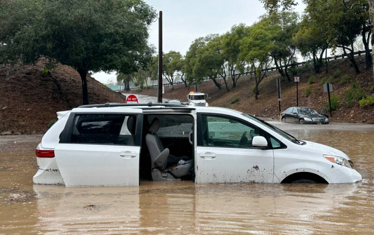 A vehicle is submerged in floodwaters near an overpass as rain comes down, Thursday, Dec. 21, 2 ...