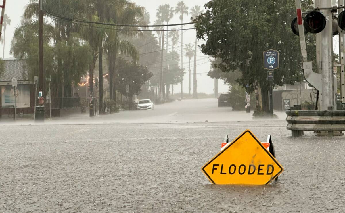 A flooded streets is shown in front of train tracks as rain comes down Thursday, Dec. 21, 2023, ...