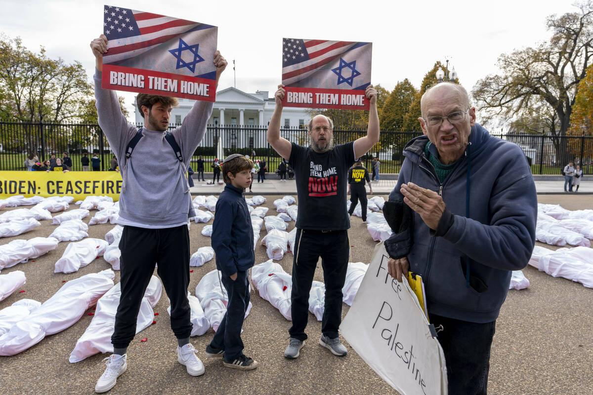 FILE - A family visiting from New Jersey holding up posters in support of bringing Israeli host ...