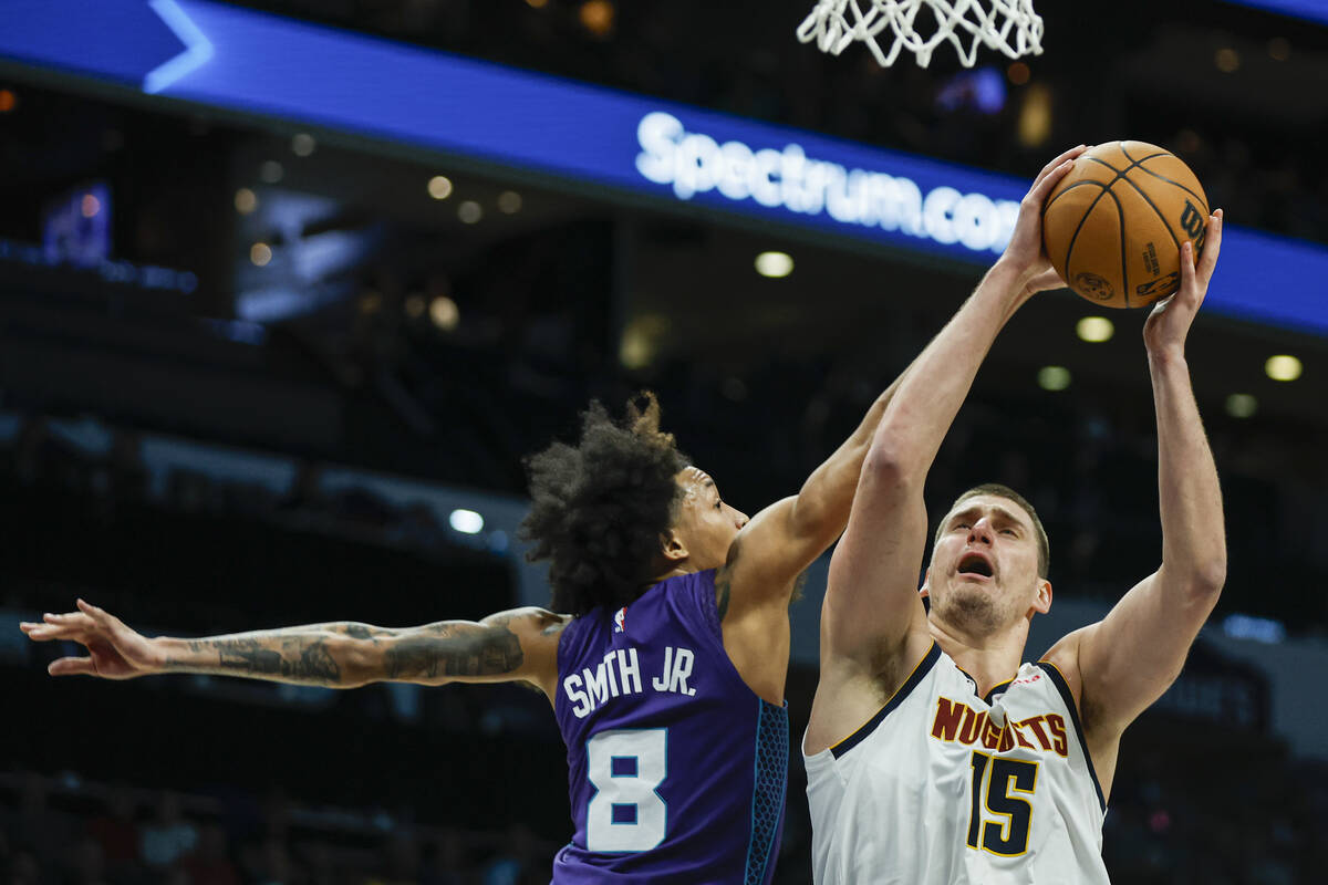 Denver Nuggets center Nikola Jokic (15) shoots against Charlotte Hornets guard Nick Smith Jr. d ...