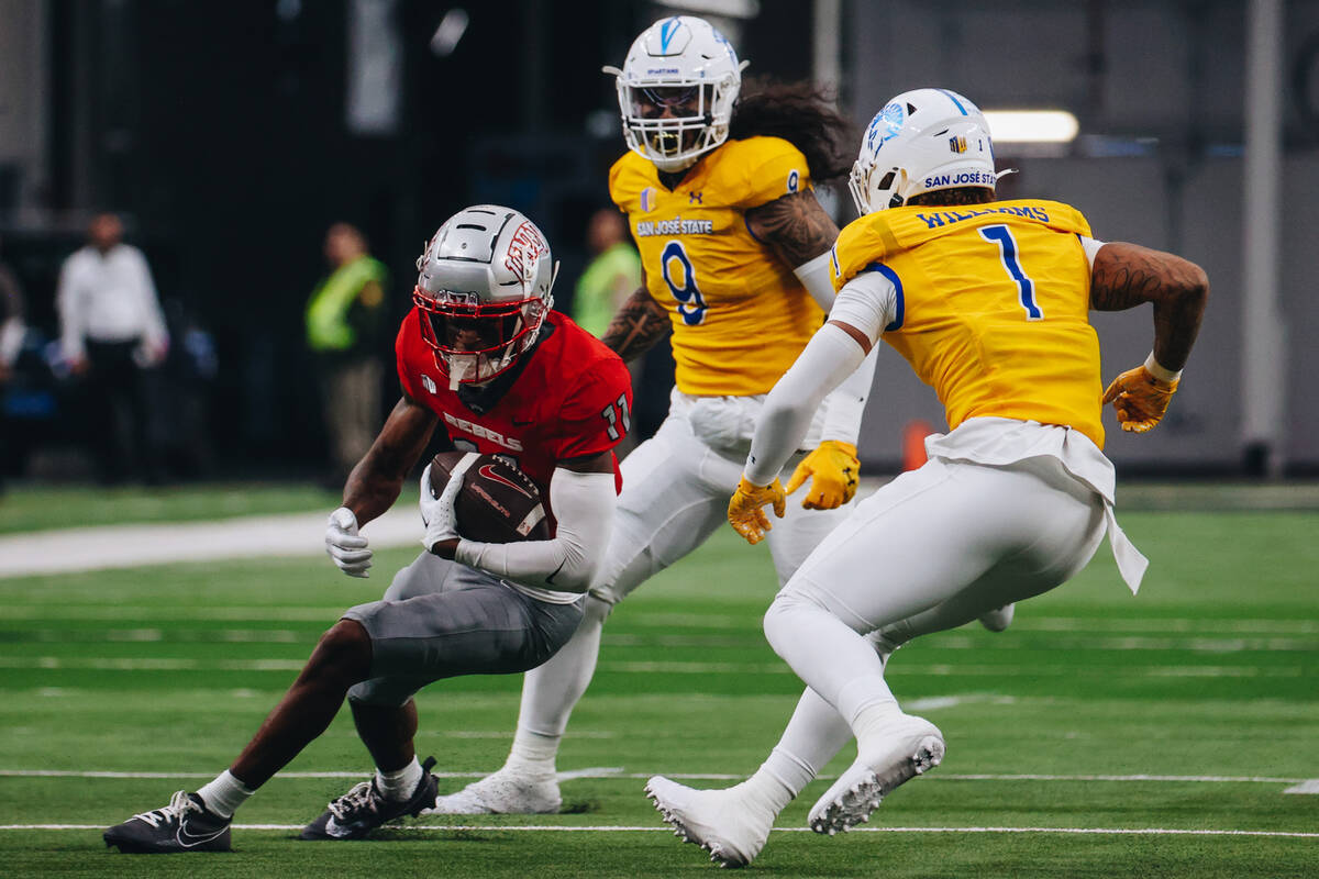 UNLV wide receiver Ricky White (11) runs the ball away from San Jose State defenders during a f ...