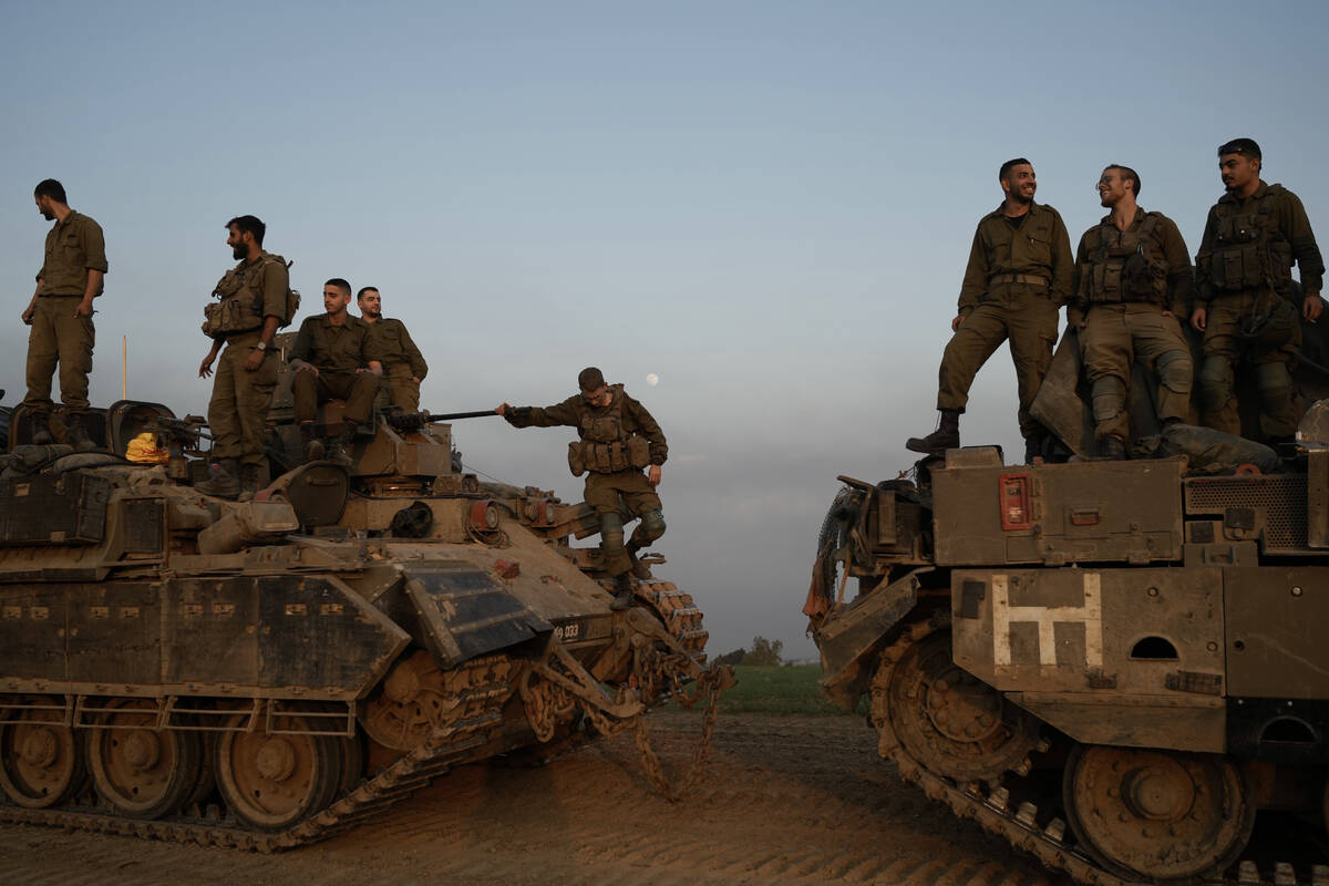 Israeli soldiers stand on top of armoured personnel carriers (APC) near the Israeli-Gaza border ...