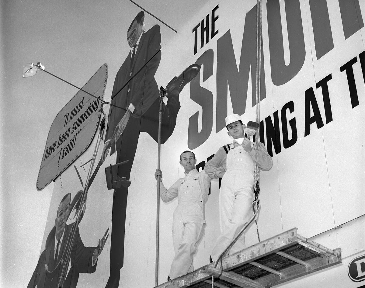 Tom, left, and Dick Smothers pose as painters next to a billboard on the Las Vegas Strip advert ...