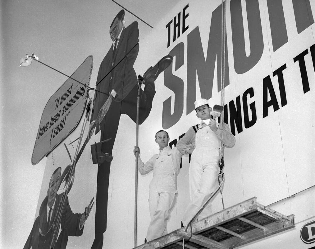 Tom, left, and Dick Smothers pose as painters next to a billboard on the Las Vegas Strip advert ...