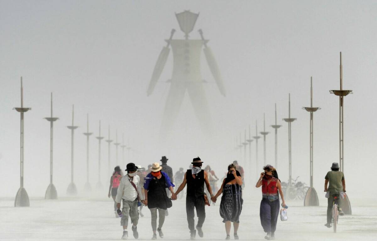 Burning Man visitors walk through dust at the annual Burning Man event on the Black Rock Desert ...