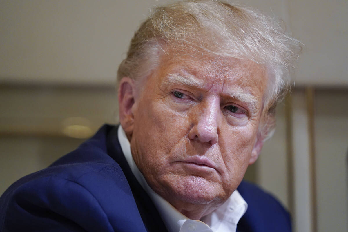 FILE - Former President Donald Trump listens as he speaks with reporters while in flight on his ...