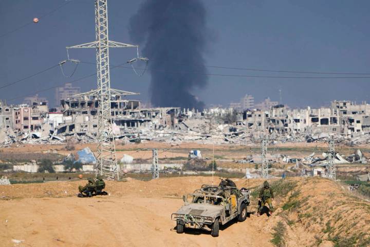 Israeli soldiers take up positions near the Gaza Strip border, as smoke rises following an Isra ...