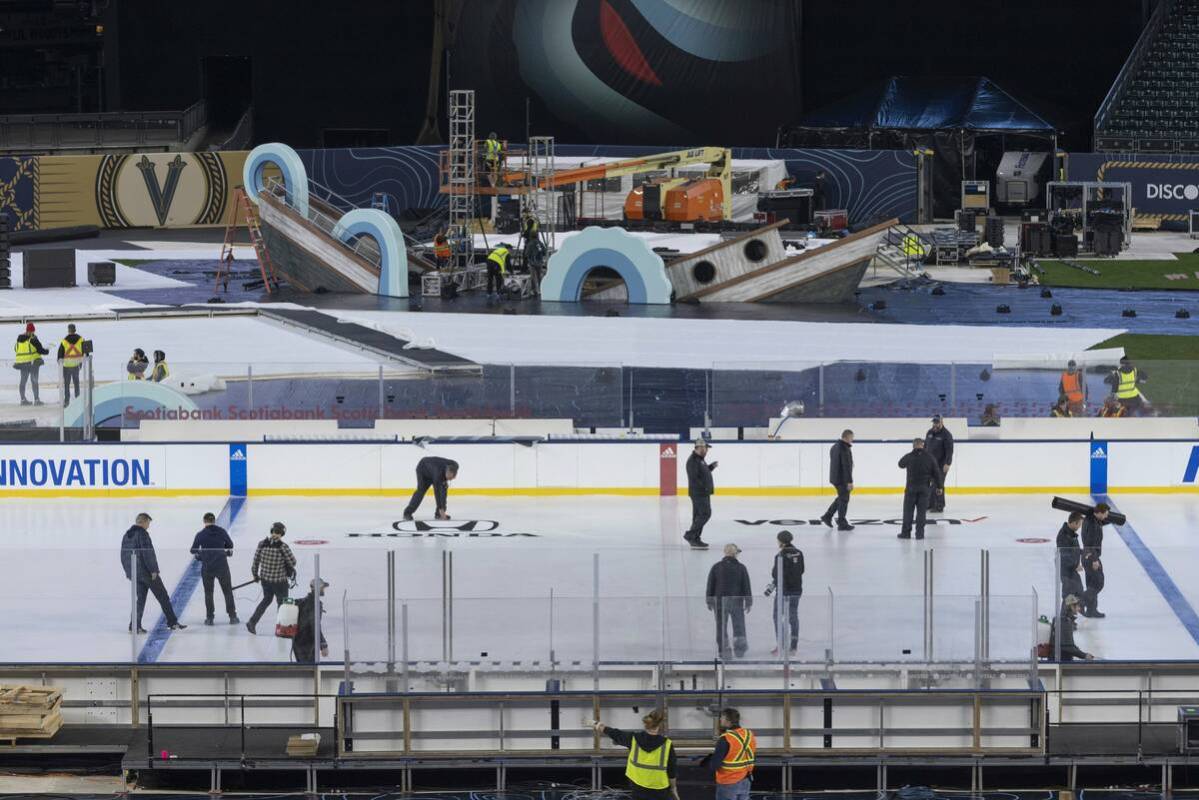 An ice crew adds lines and logos to the NHL Winter Classic ice skating rink at T-Mobile Park in ...