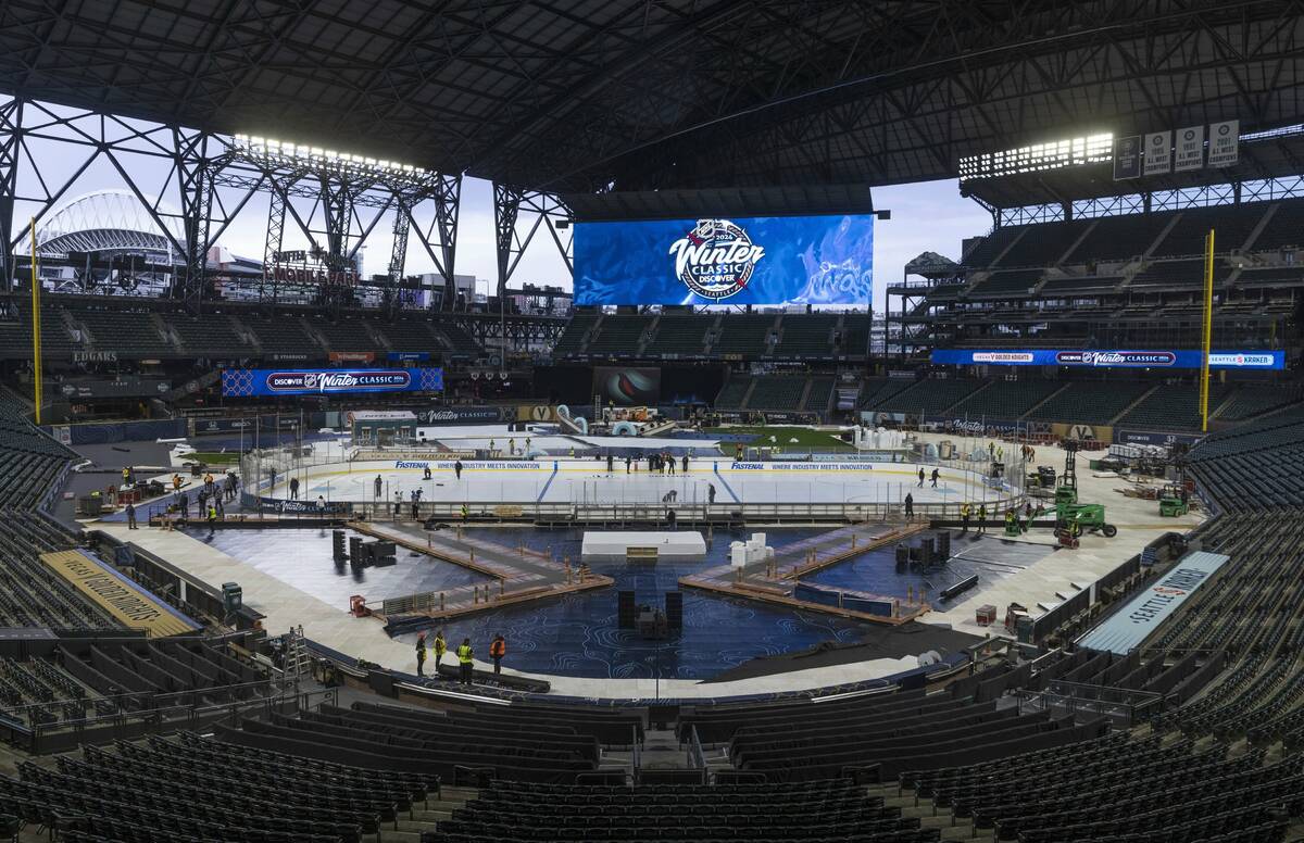 An ice crew adds lines and logos to the NHL Winter Classic ice skating rink at T-Mobile Park in ...