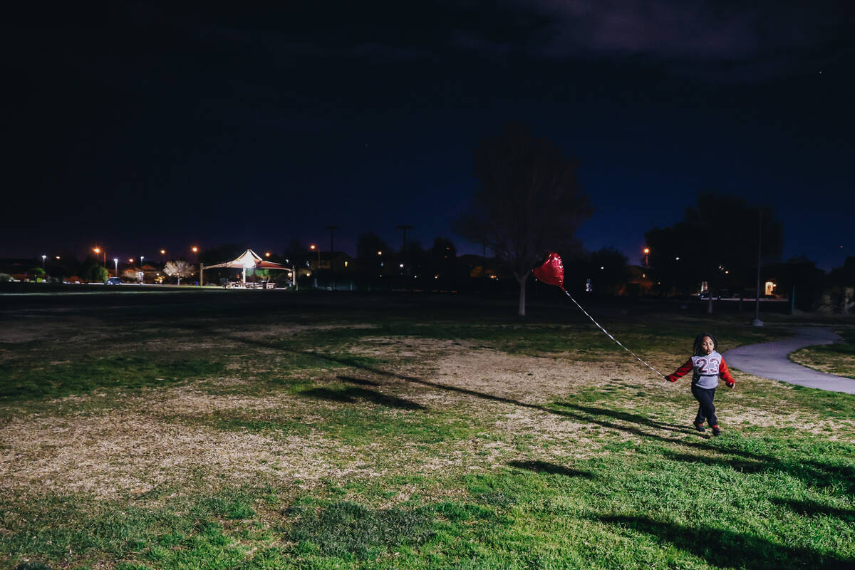 A child carries a balloon to a vigil for Keon Young at Desert Horizons Park on Friday, Dec. 29, ...