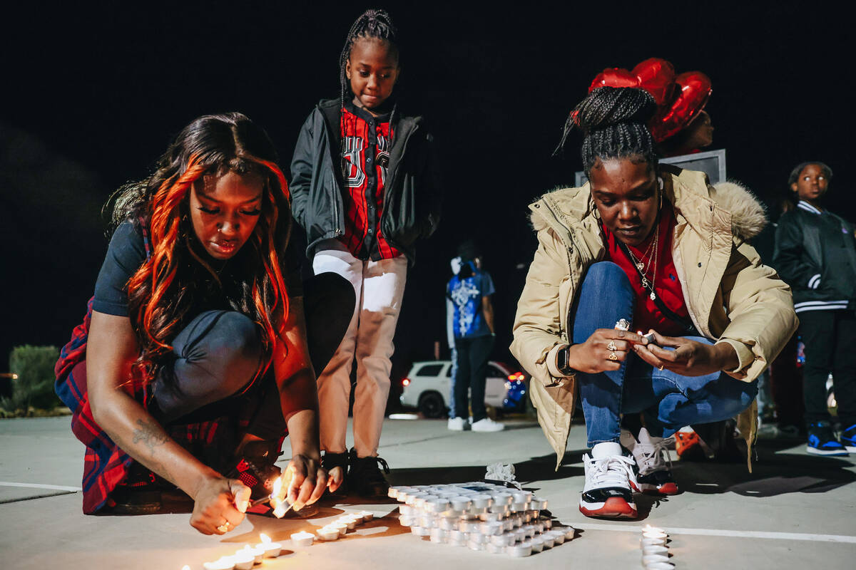 Jasmine McClenon, left, lights candles with Shana Jones, right, during a vigil for Keon Young a ...