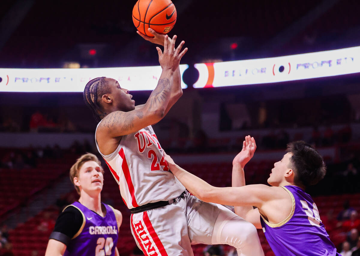 UNLV Rebels guard Jackie Johnson III (24) is fouled by Carroll College Fighting Saints guard Jo ...