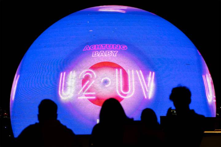 Spectators photograph The Sphere while it shows an advertisement for its opening show, U2, as s ...