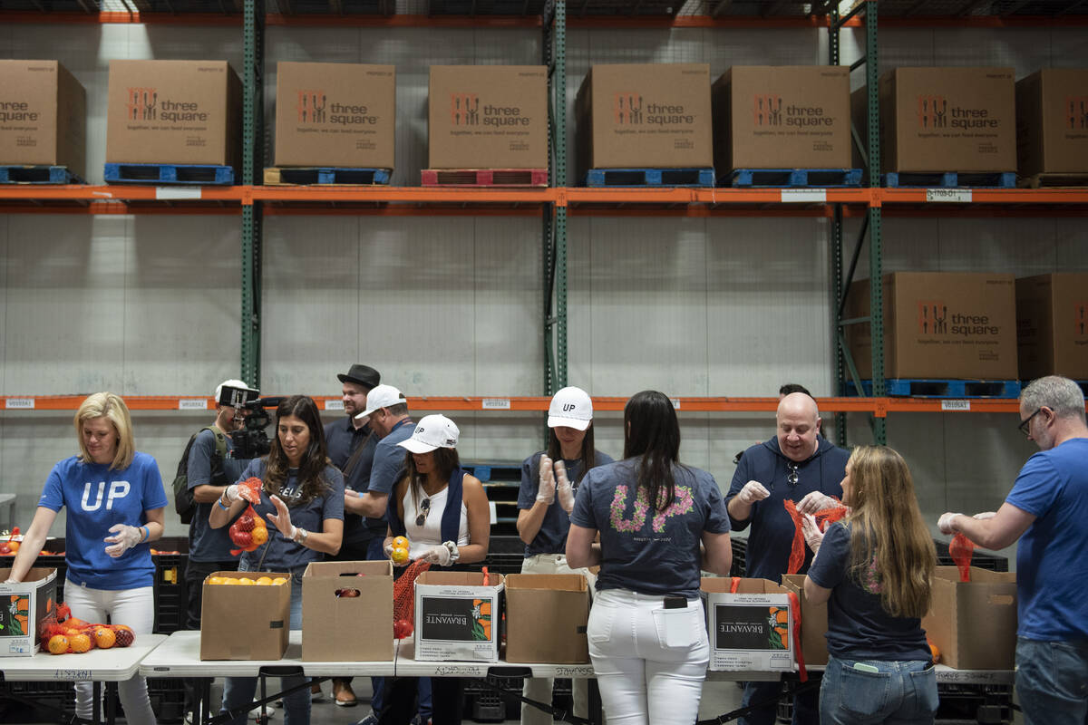 Volunteers pack bags of fruit to be distributed to seniors at Three Square food bank on June 1, ...