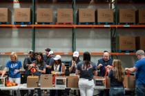 Volunteers pack bags of fruit to be distributed to seniors at Three Square food bank on June 1, ...