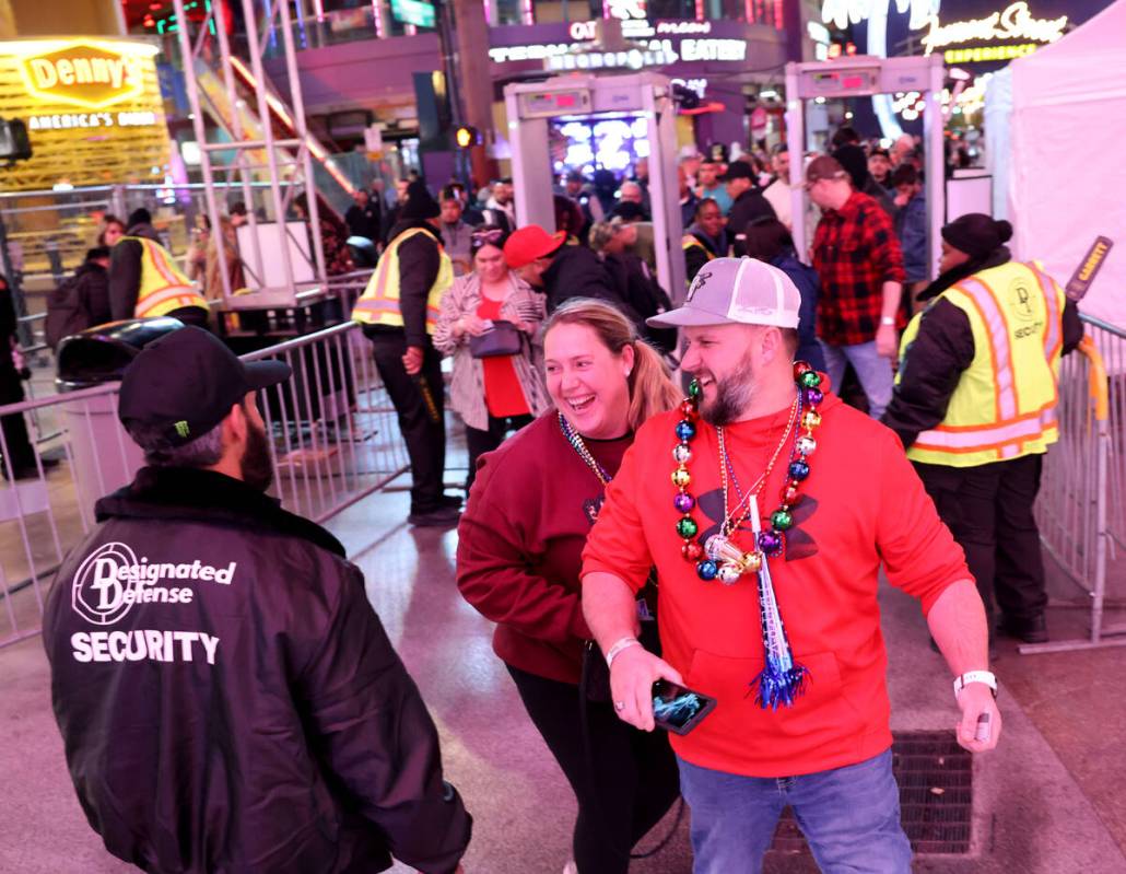 New Year’s Eve revelers Mike and Lissette Shelton of Colbert, Okla. laugh with a guard a ...