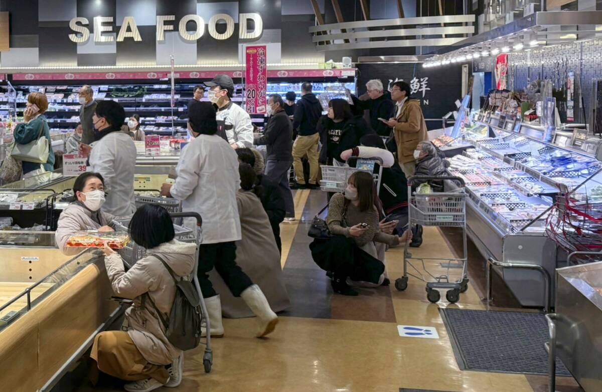 Customers crouch following an earthquake at a supermarket in Toyama, Japan Sunday, Jan. 1, 2024 ...