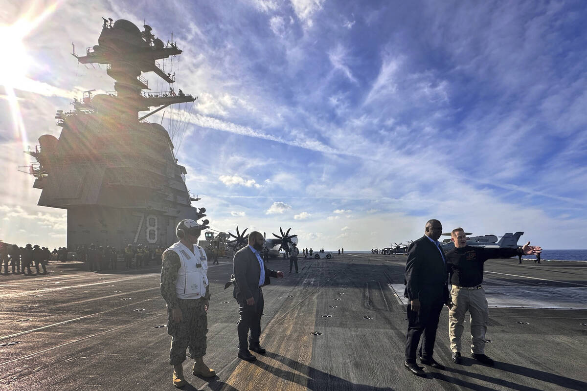 Defense Secretary Lloyd Austin, second right, talks with the commanding officer of the USS Gera ...