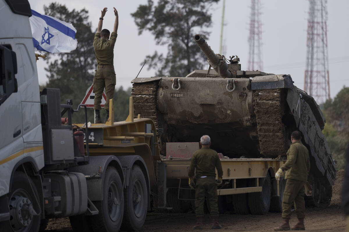 Israeli soldiers load a tank on a transport truck in a staging area at the Israeli-Gaza border ...