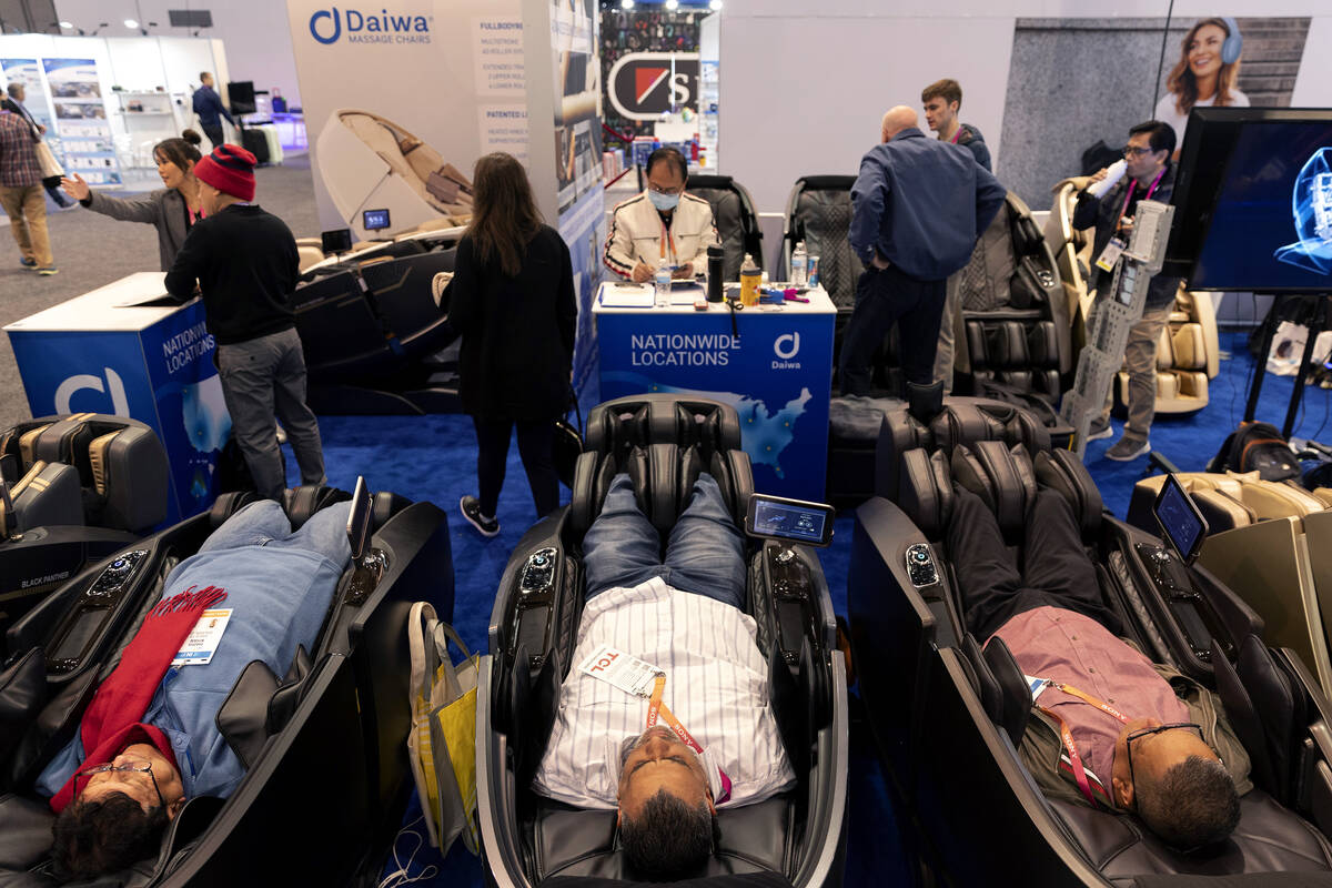 Attendees relax in Daiwa massage chairs at the company’s booth during the CES tech show ...