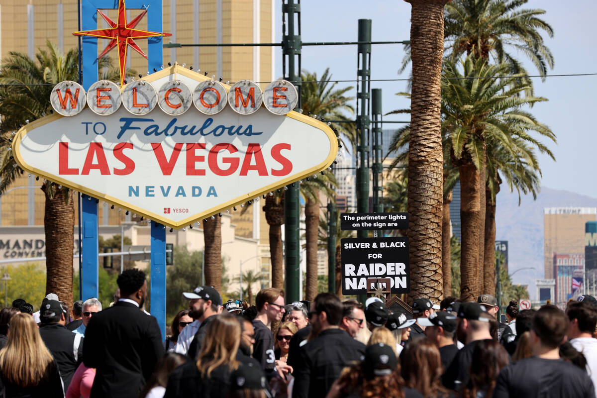 Raiders staff gather at the Welcome to Fabulous Las Vegas sign for a ceremony to light the peri ...