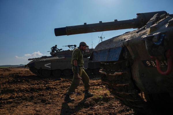 Israeli soldiers work on their tank in a staging area at the Israeli-Gaza border in southern Is ...