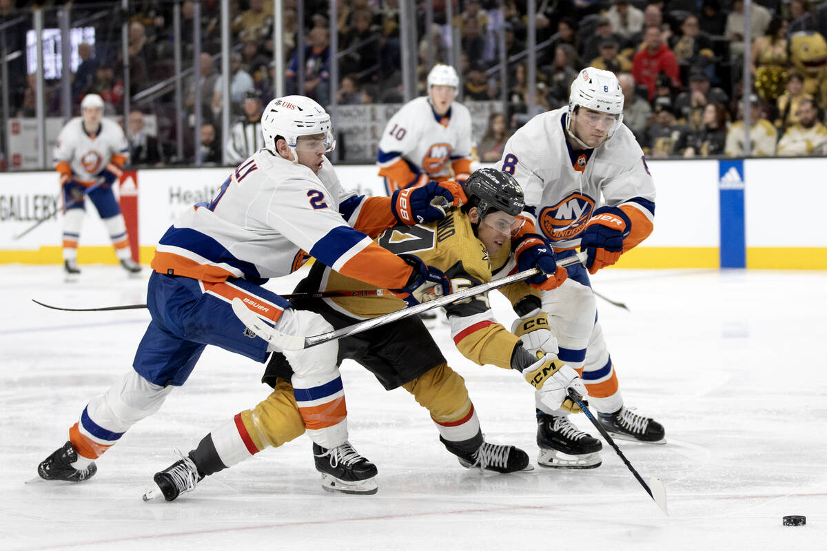 Golden Knights left wing Grigori Denisenko (54) battles for the puck between Islanders defensem ...