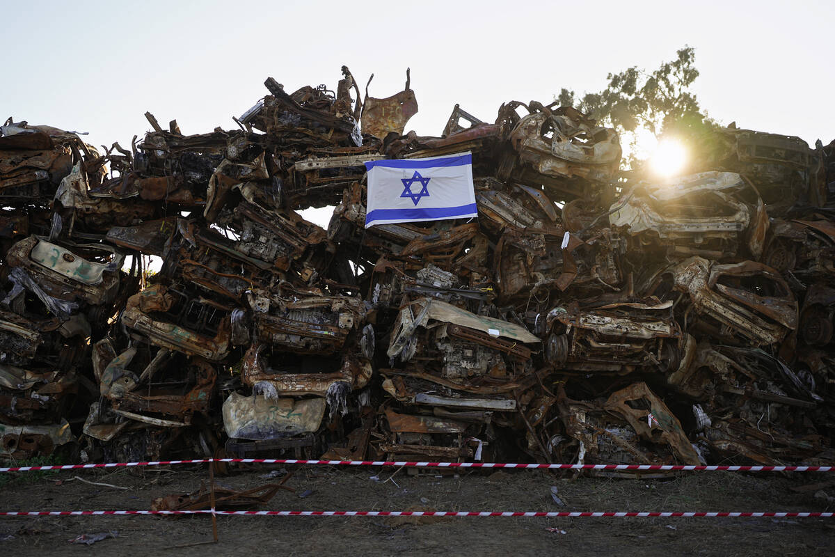 An Israeli flag is placed on a pile of charred vehicles burned in the bloody Oct. 7 cross-borde ...