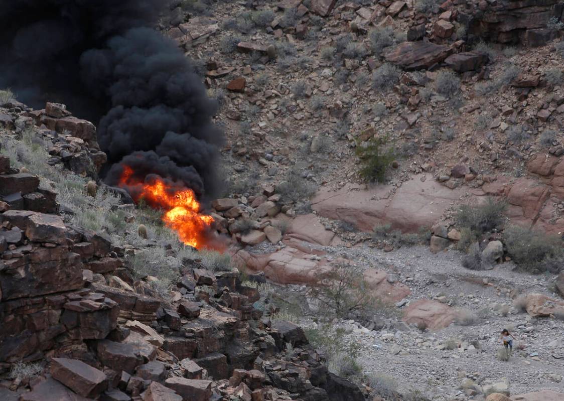 FILE - A survivor, lower right, walks away from the scene of a deadly tour helicopter crash alo ...