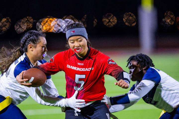 Desert Oasis quarterback Akemi Higa (5) looks to gets through Shadow Ridge defenders Jaylani Pa ...