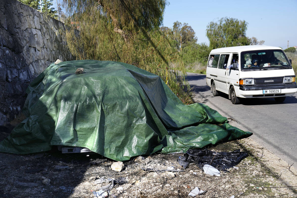 A school bus passes by the covered burned and damaged car that was used by the senior Hezbollah ...